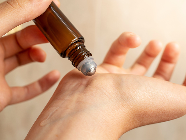 A pair of hands applying an essential oil roll-on to the inner wrists