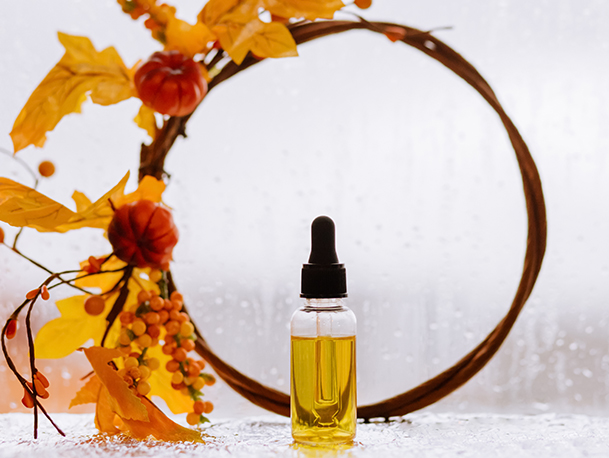 Bottle of essential oil in front of an orange pumpkin wreath