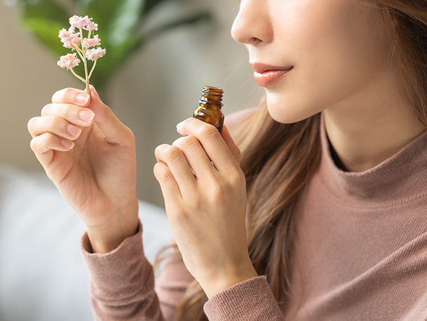 A Woman smelling bottle of essential oil / perfume scent